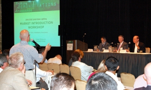 Photo of speakers facing an audience, with a member of the audience asking a question.